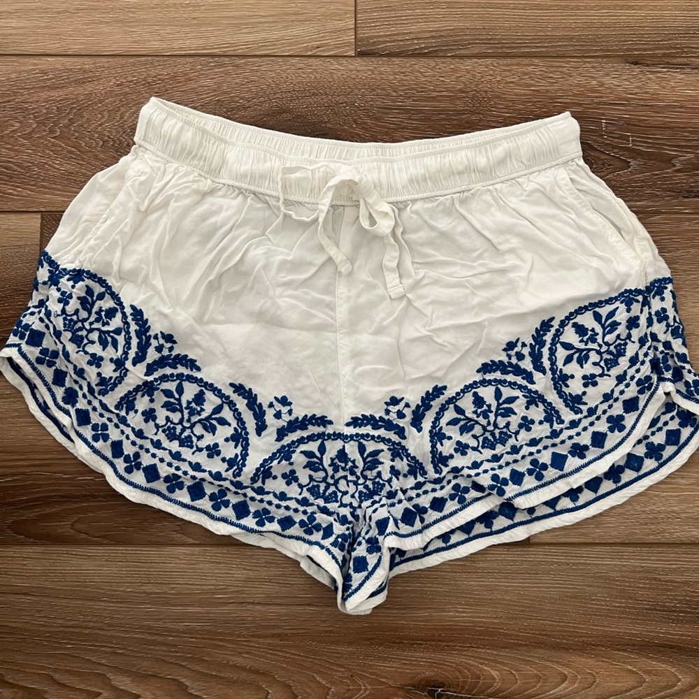 White flowy shorts with blue detailed stitching.